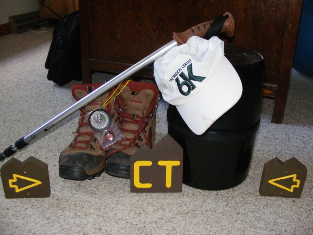 hiking gear: boots, hat, trekking pole, and bear canister