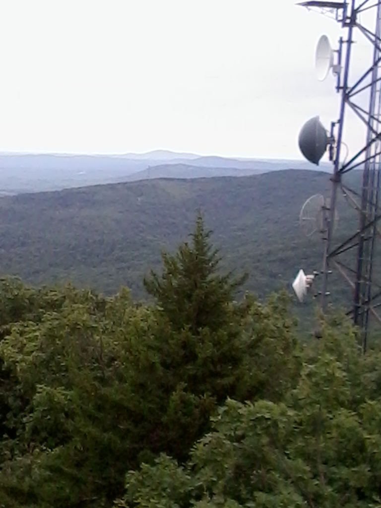 Cell tower on mountaintop with view to distant hills