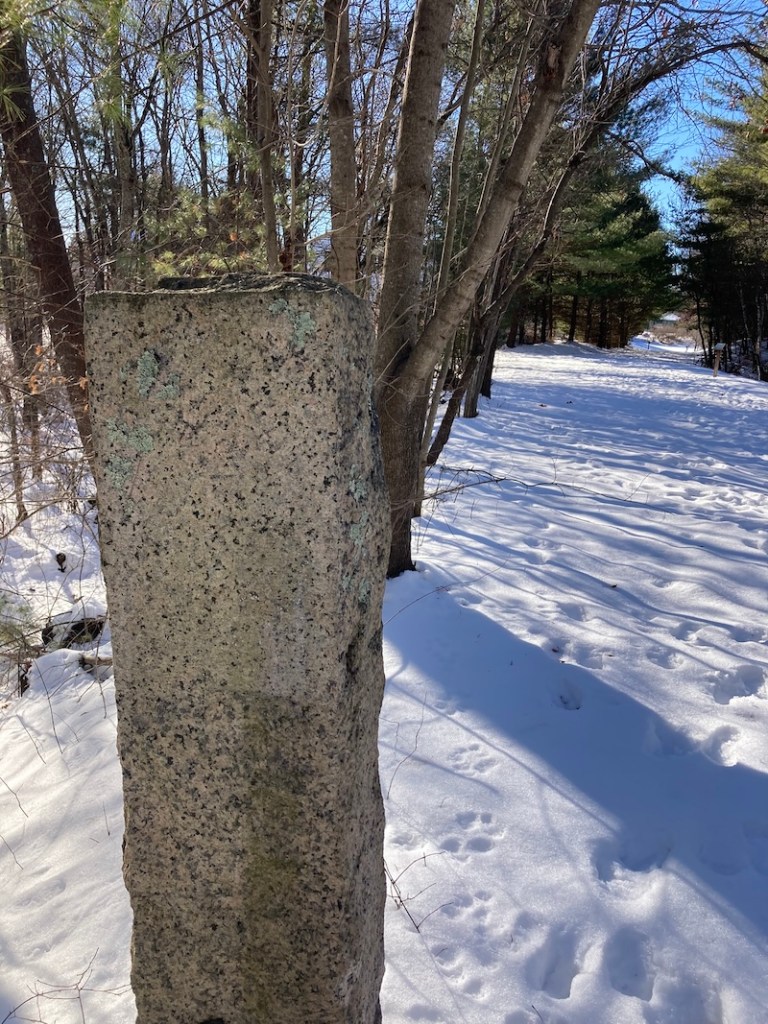 Granite post along a snow-covered rail trail